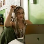 a woman with dreadlocks sitting in front of a laptop computer